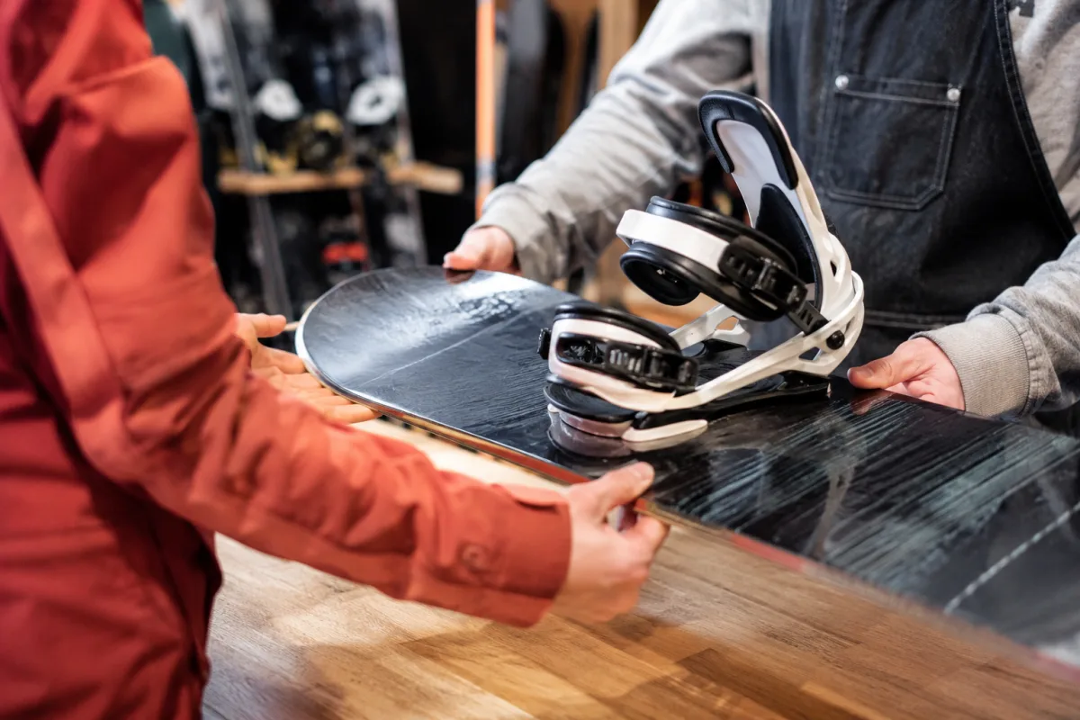 Gros plan sur des fixations de snowboard réglées sur une planche posée dans la neige
